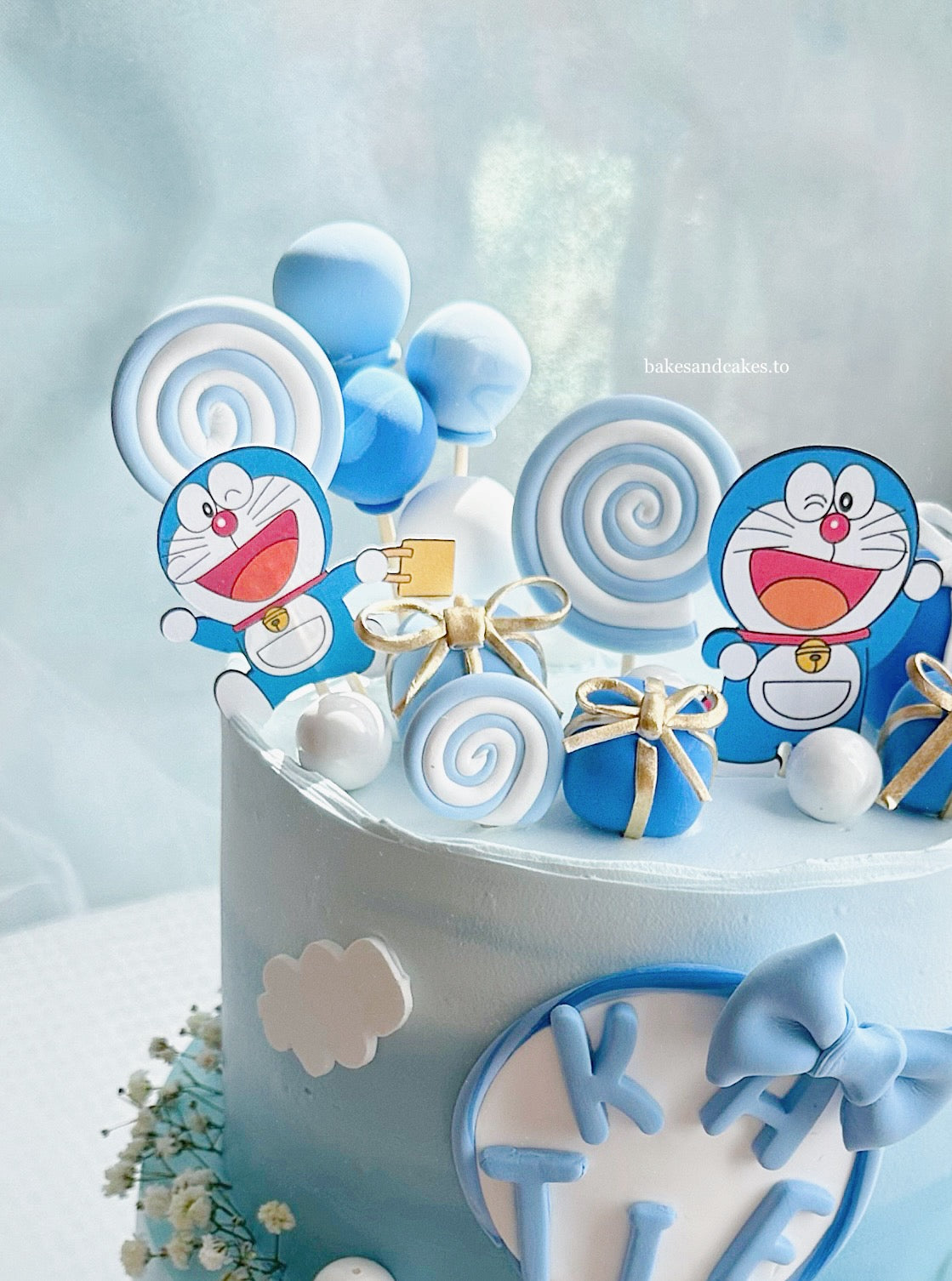 Doraemon two-tier birthday cake side view with character toppers and cream detailing